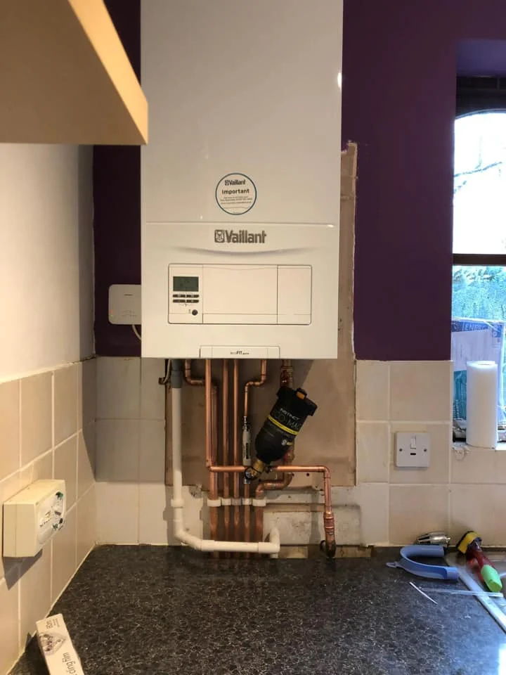 New A-rated Vaillant gas boiler installation with copper and plastic piping in a domestic kitchen setting, showcasing energy-efficient heating solutions for homes in Hornchurch.