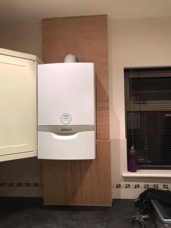 Gas boiler installation by T.M.S. Mechanical Services in a domestic kitchen, featuring a Vaillant boiler mounted on a wooden backdrop, illustrating modern heating solutions for homes in Dagenham.