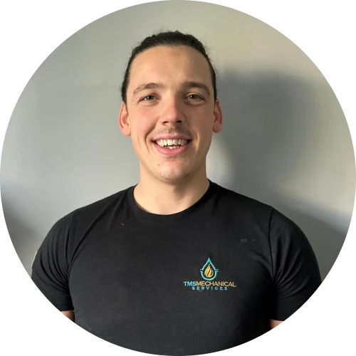 Danny Whiting, team member at T.M.S. Mechanical Services, smiling in a black branded t-shirt against a neutral background.