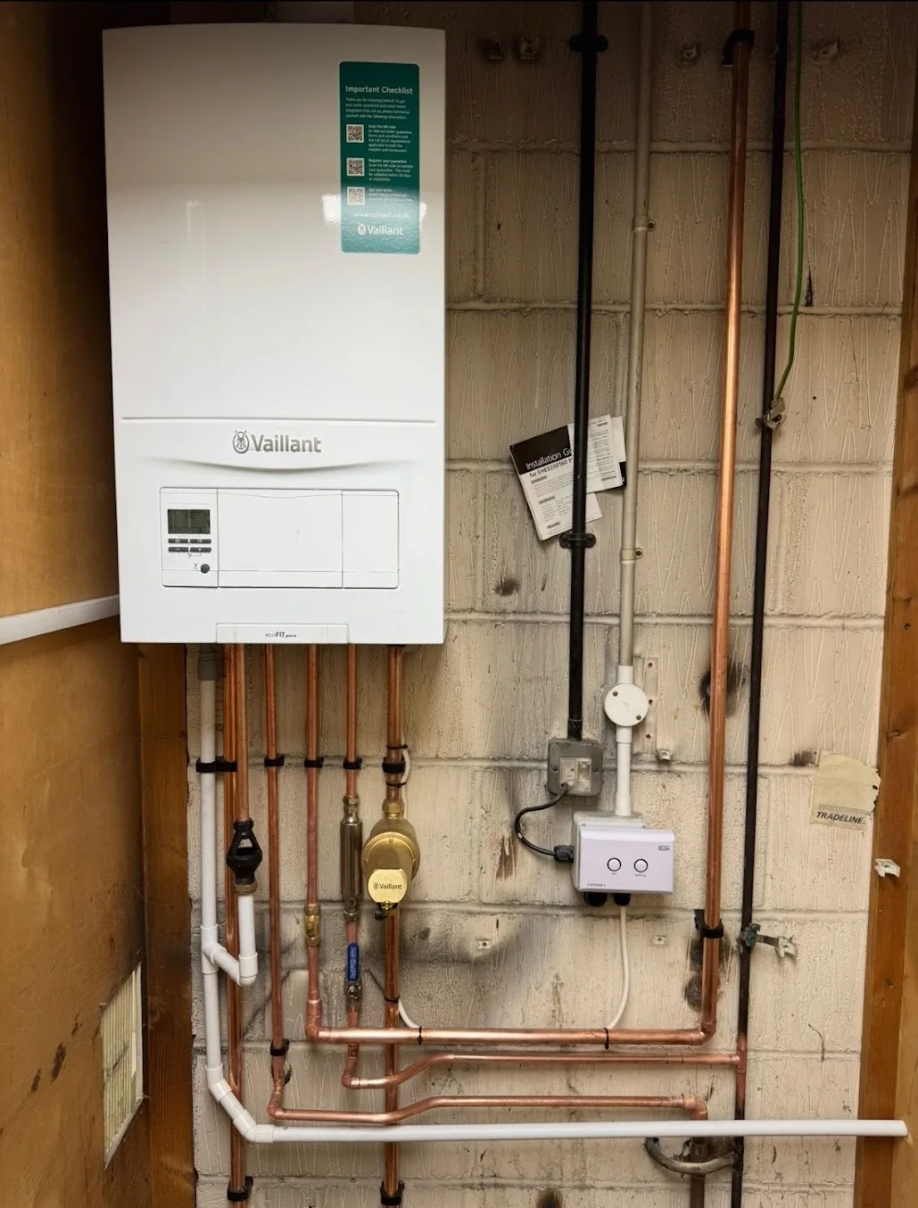 Vaillant gas boiler installation with copper and plastic piping in a residential setting, showcasing modern heating technology for energy efficiency.