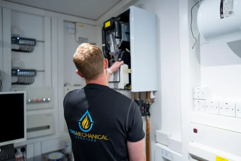 Technician from TMS Mechanical Services inspecting a boiler installation in a service area, showcasing expertise in heating solutions and maintenance.