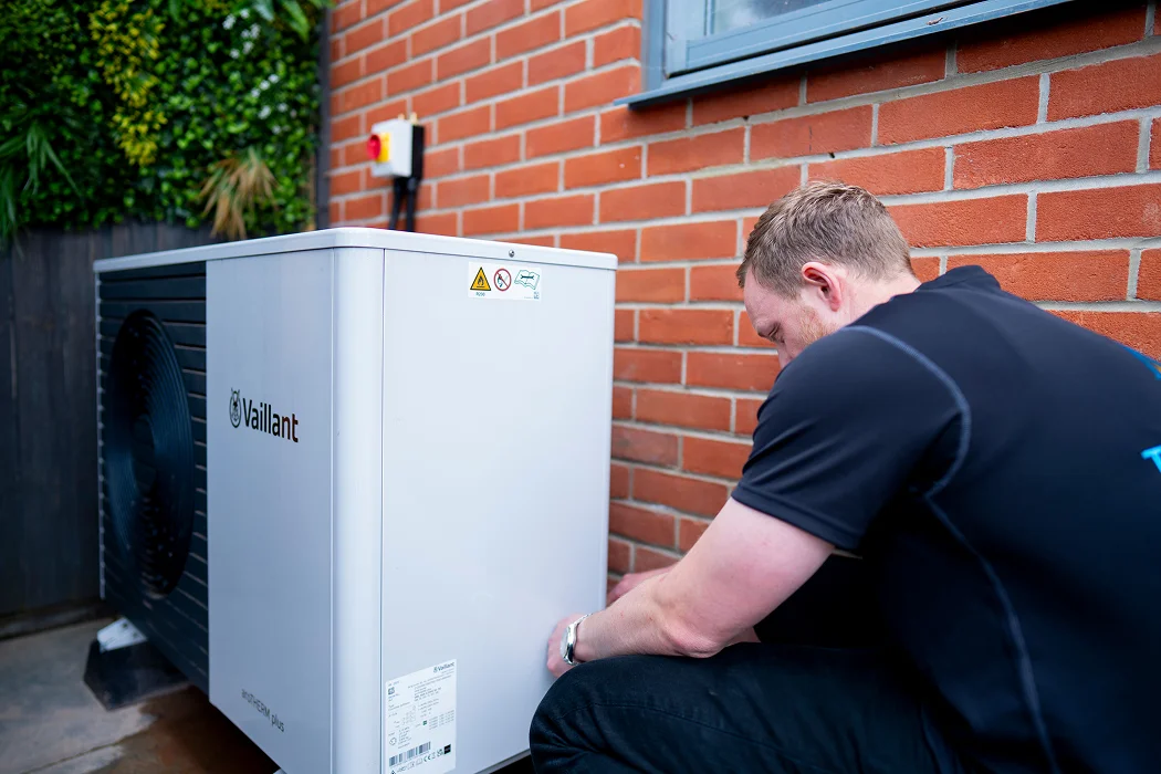 Technician installing a Vaillant air source heat pump against a brick wall in Dagenham, showcasing eco-friendly heating solutions.